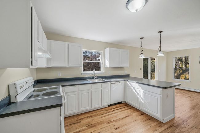 Kitchen with white cabinetry, a sink, dark countertops, and white appliances | Image 12