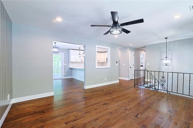Empty room with ceiling fan with notable chandelier and dark wood-type flooring | Image 7