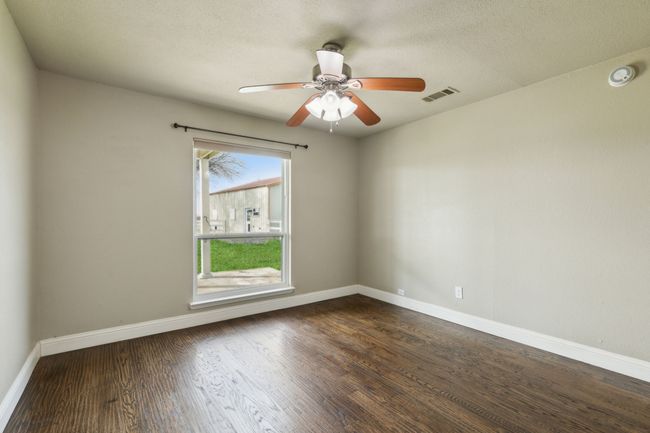 Spare room featuring a ceiling fan, wood finished floors, visible vents, baseboards, and a textured ceiling | Image 6