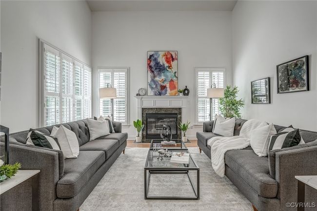 The light-filled, two-story family room features a cozy gas fireplace and plantation shutters, creating an inviting space for everyday living. | Image 19