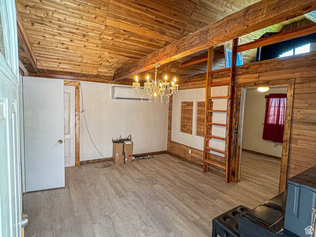 Unfurnished room featuring wood ceiling, wood-type flooring, beamed ceiling, a chandelier, and a wood stove | Image 14
