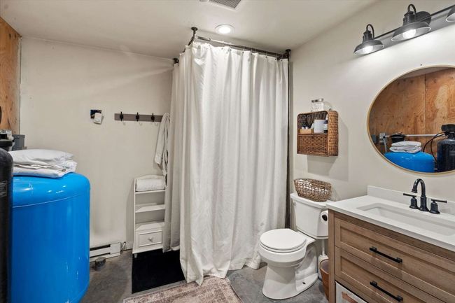 Bathroom with concrete flooring, vanity, baseboard heating, and a shower with shower curtain | Image 24