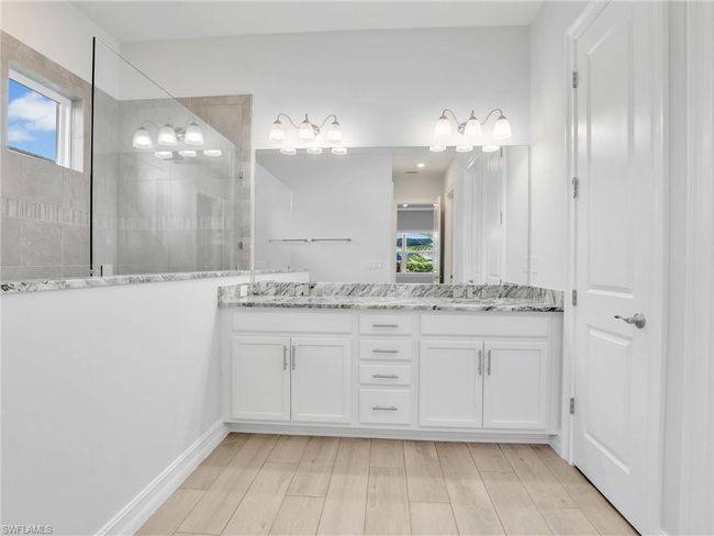 Bathroom featuring a wealth of natural light, vanity, wood-type flooring, and tiled shower | Image 23