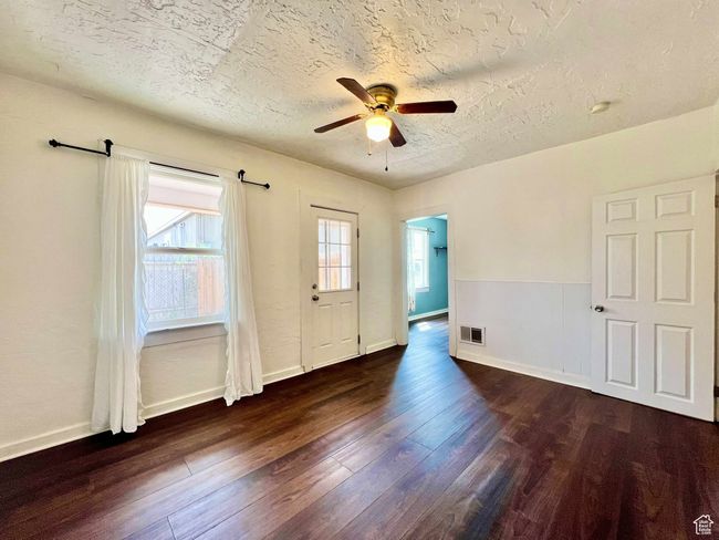 Spare room featuring dark wood-style floors, a textured ceiling, visible vents, baseboards, and ceiling fan | Image 11