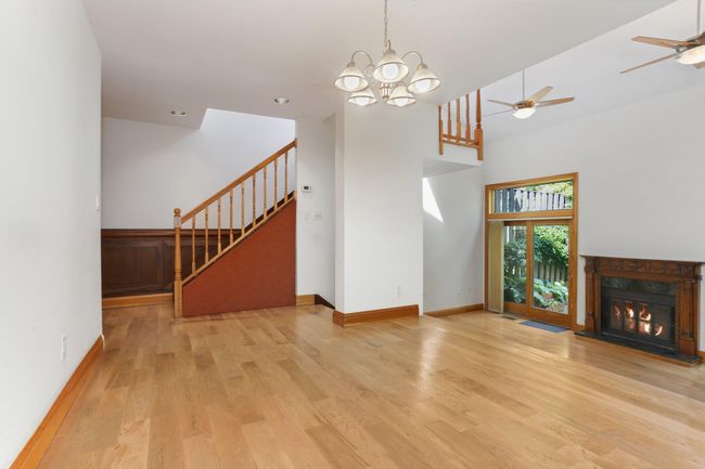Unfurnished living room with stairs, wood finished floors, a high end fireplace, a chandelier, and ceiling fan | Image 10