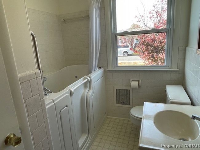 Full bathroom with toilet, sink, tile walls, and shower / tub combo | Image 19