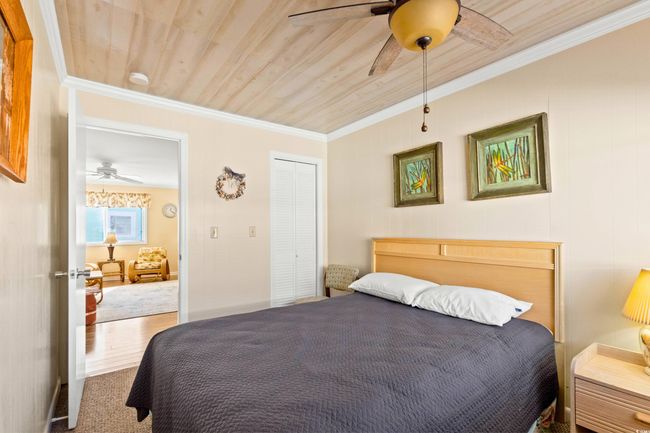 Carpeted bedroom with ceiling fan, a closet, wood ceiling, and ornamental molding | Image 16