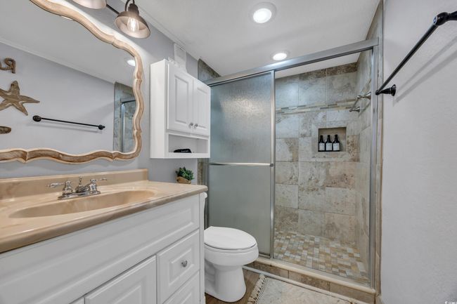Bathroom with a shower stall, vanity, toilet, tile patterned flooring, and recessed lighting | Image 7
