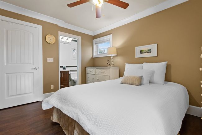 Bedroom with dark wood-style flooring, ensuite bath, ceiling fan, crown molding, and baseboards | Image 21