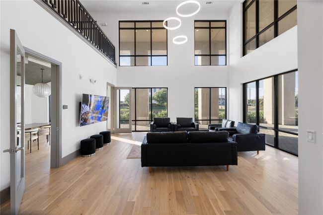 Living area with light wood-style floors, a high ceiling, and baseboards | Image 29