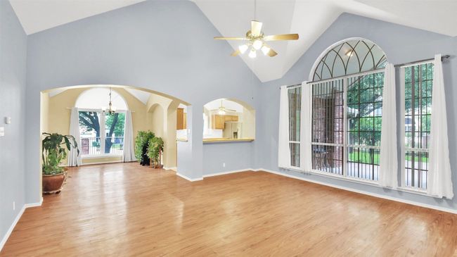 Living room featuring a chandelier, light vinyl plank floors, ceiling fan, high vaulted ceiling, and arched walkways | Image 10
