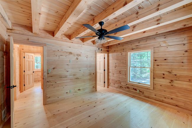 Unfurnished room with light wood-style floors, wood walls, wood ceiling with exposed beams, and a ceiling fan | Image 24