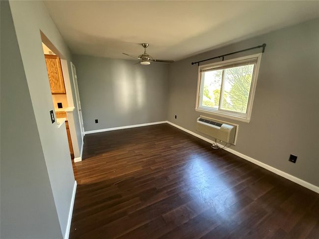 Spare room with dark wood finished floors, an AC wall unit, a ceiling fan, and baseboards | Image 4