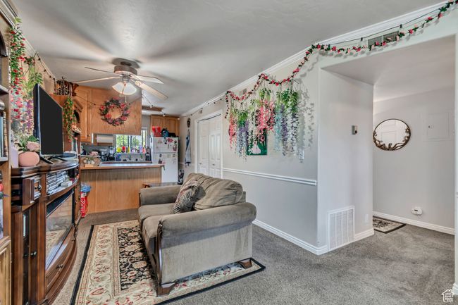 Living area with a ceiling fan, carpet floors, and crown molding | Image 5