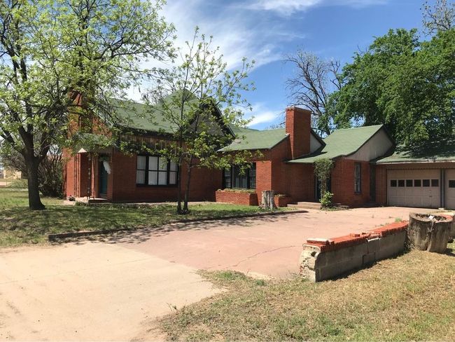 Single story home with concrete driveway, a chimney, a front lawn, an attached garage, and brick siding | Image 19