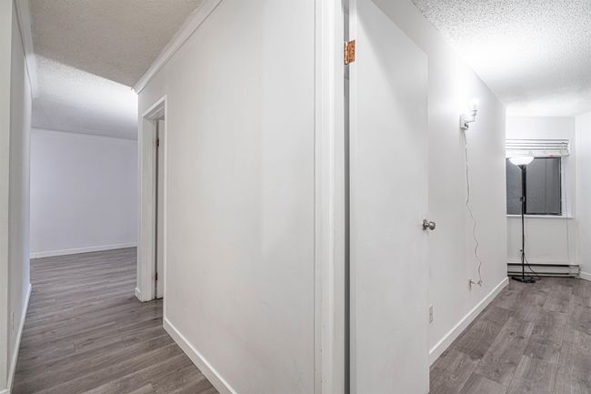 Corridor with baseboard heating, a textured ceiling, baseboards, and wood finished floors | Image 21