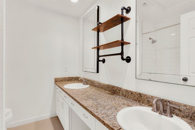 Bathroom with double vanity, tile patterned floors, and tiled shower | Image 13