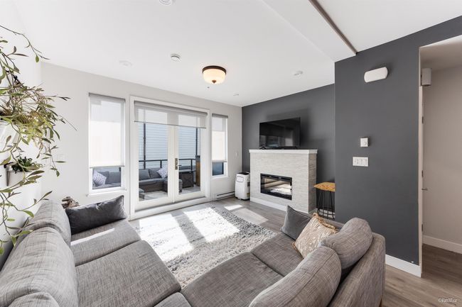 Living area with a baseboard heating unit, a stone fireplace, wood finished floors, and baseboards | Image 11