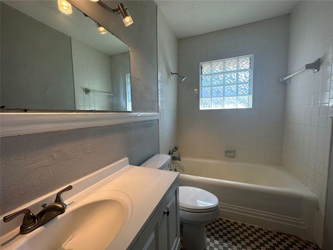 Bathroom featuring a textured wall, shower / bath combination, vanity, and toilet | Image 5