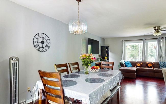 Dining space with dark wood finished floors, a chandelier, and ceiling fan | Image 17
