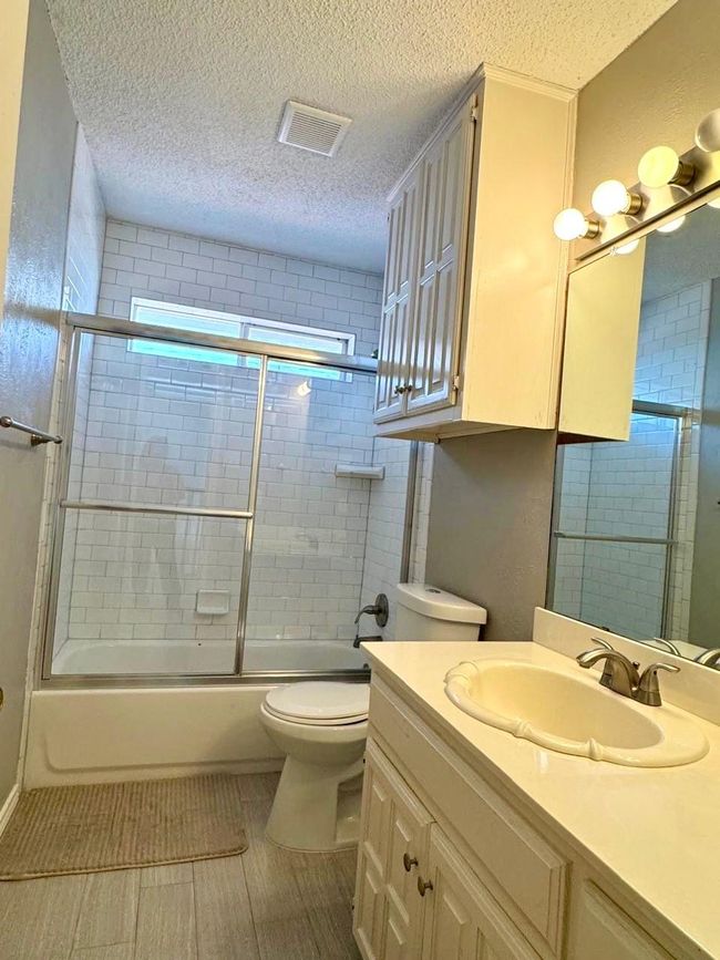 Full bath featuring visible vents, a textured ceiling, and toilet | Image 16
