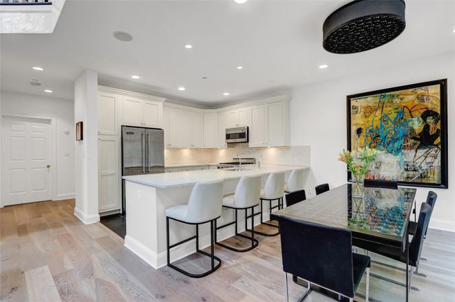 Kitchen featuring appliances with stainless steel finishes, light countertops, backsplash, white cabinets, and light wood-style flooring | Image 11