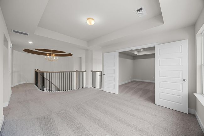 Carpeted empty room with a tray ceiling, baseboards, a chandelier, and recessed lighting | Image 23