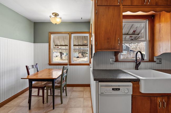 The kitchen features a cozy dining area and a large, deep sink with a window facing the front yard. | Image 4