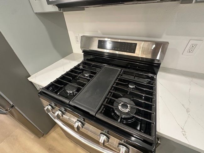 Kitchen view of gas stove and light stone countertops | Image 10