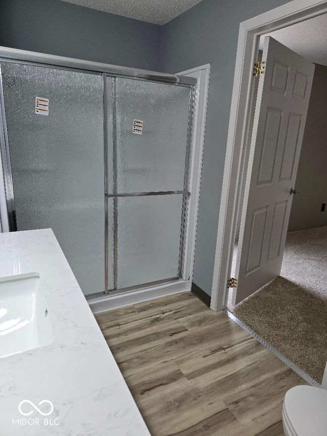 full bath with toilet, a stall shower, a textured ceiling, wood finished floors, and vanity | Image 20