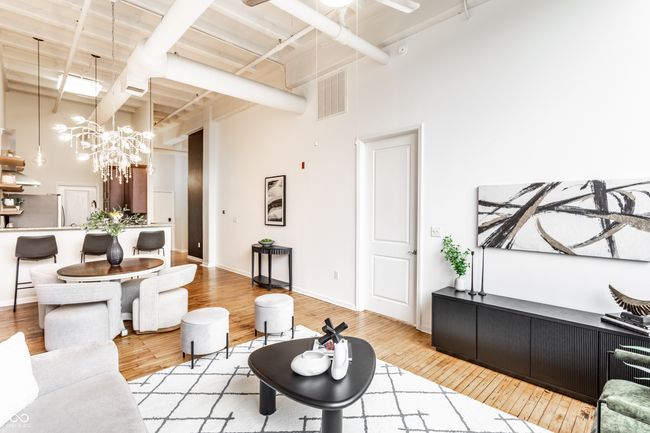 living area featuring a towering ceiling, wood finished floors, and a chandelier | Image 7