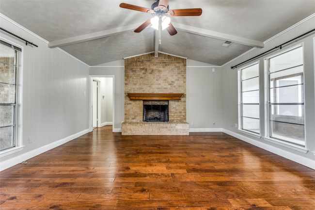 Unfurnished living room featuring hardwood / wood-style floors, a ceiling fan, and a fireplace | Image 4