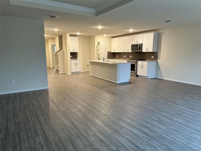 Kitchen with appliances with stainless steel finishes, ornamental molding, open floor plan, dark wood-type flooring, and recessed lighting | Image 6