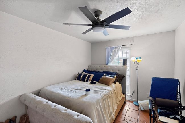 Bedroom with light tile patterned floors, ceiling fan, and a textured ceiling | Image 11
