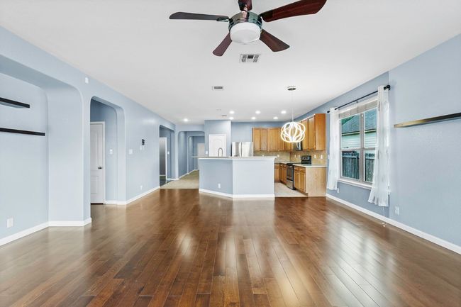 Unfurnished living room featuring a ceiling fan, dark wood-style floors, arched walkways, and recessed lighting | Image 11