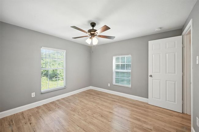 Empty room featuring light wood finished floors, a smoke detector, and a ceiling fan | Image 10