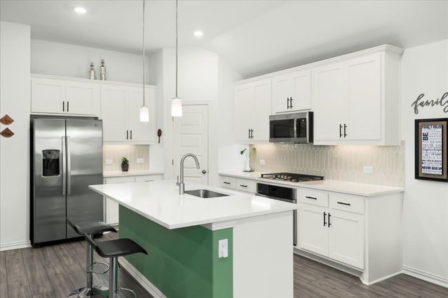 Kitchen featuring a center island with sink, a sink, stainless steel appliances, light countertops, and white cabinetry | Image 18