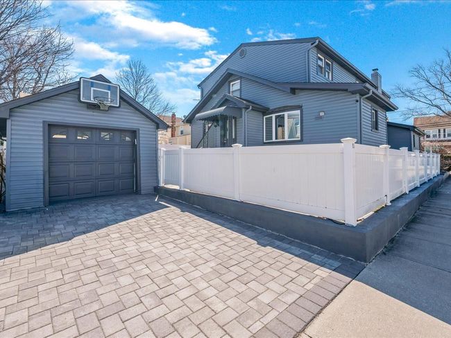 View of side of property with an outdoor structure, a garage, decorative driveway, and a chimney | Image 33