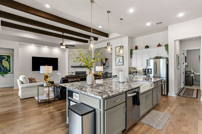 Kitchen with stainless steel appliances, visible vents, hanging light fixtures, a kitchen island with sink, and white cabinets | Image 15