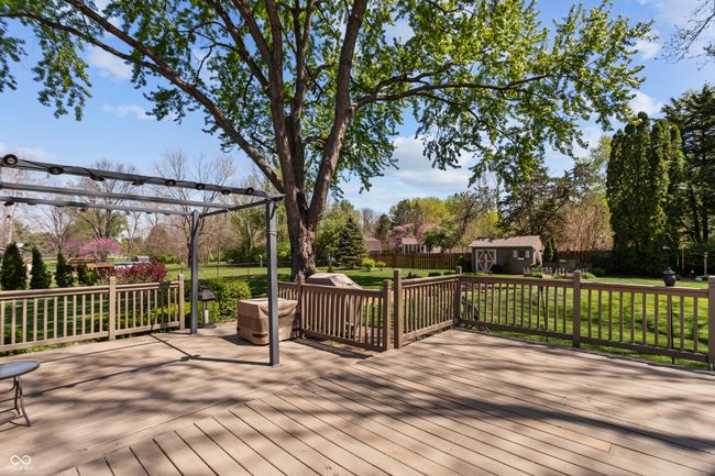 wooden deck with a lawn, an outdoor structure, a storage unit, and a fenced backyard | Image 36