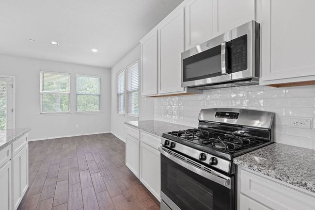 Kitchen with stainless steel appliances, dark wood-type flooring, decorative backsplash, white cabinets, and recessed lighting | Image 14