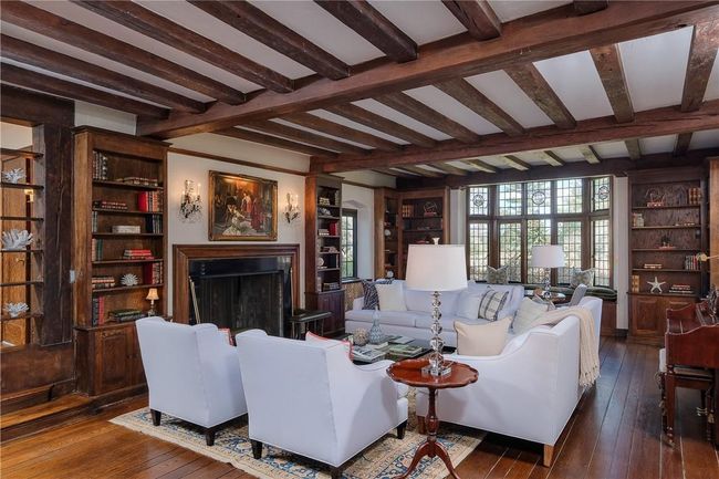 Formal living room, beamed ceiling, fireplace flanked by built-in bookcases, window seat with leaded glass windows, wide board oak hardwood floors, French doors to covered loggia | Image 9