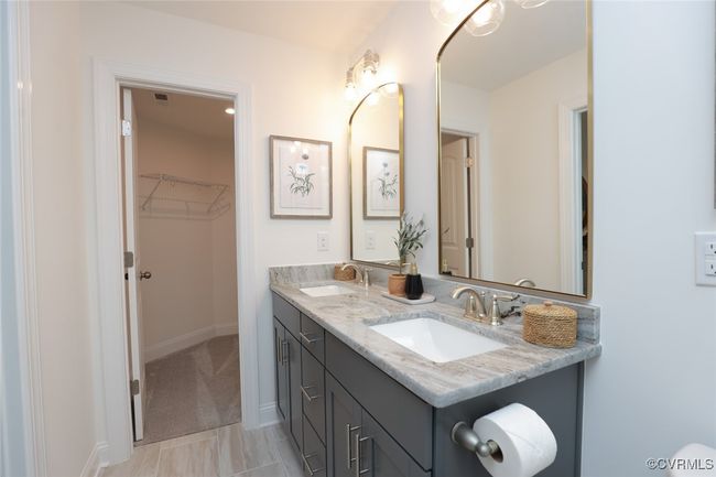 The private, first-floor primary suite is tucked away at the back of the home and offers a tray ceiling, walk-in closet and an ensuite bath with luxury shower and double vanity. | Image 5