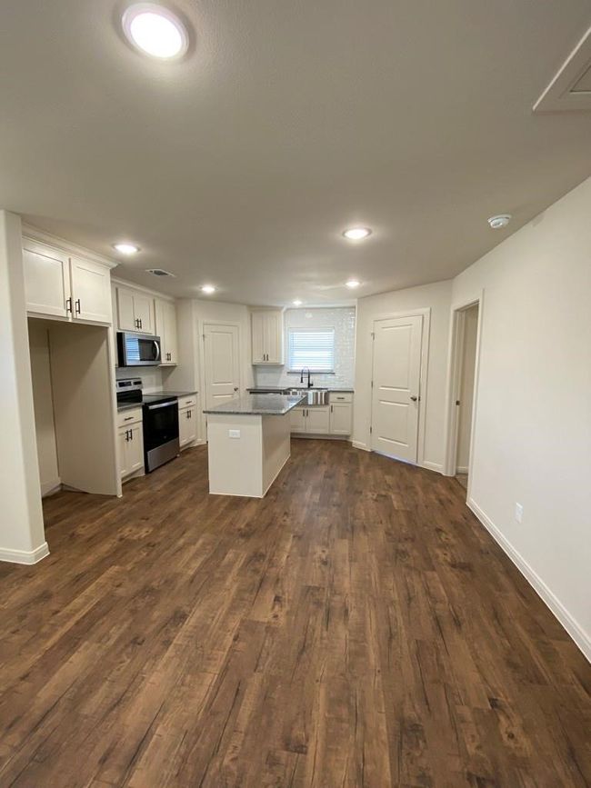 Kitchen with stainless steel appliances, dark wood-style floors, white cabinets, a sink, and recessed lighting | Image 4