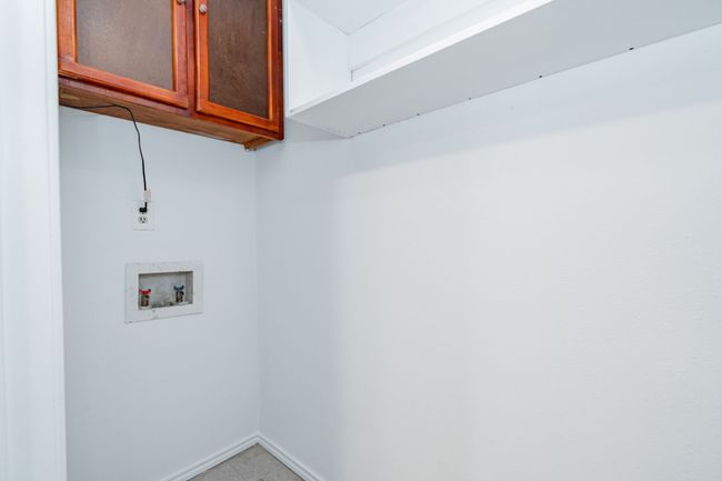 Laundry area featuring washer hookup, baseboards, cabinet space, and light tile patterned floors | Image 25