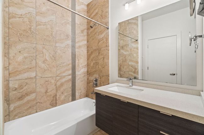 Primary bathroom has a large tub/shower combo and a vanity with ample countertop space. | Image 5