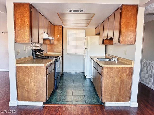 Kitchen featuring black stove, a sink, baseboards, and brown cabinetry | Image 4