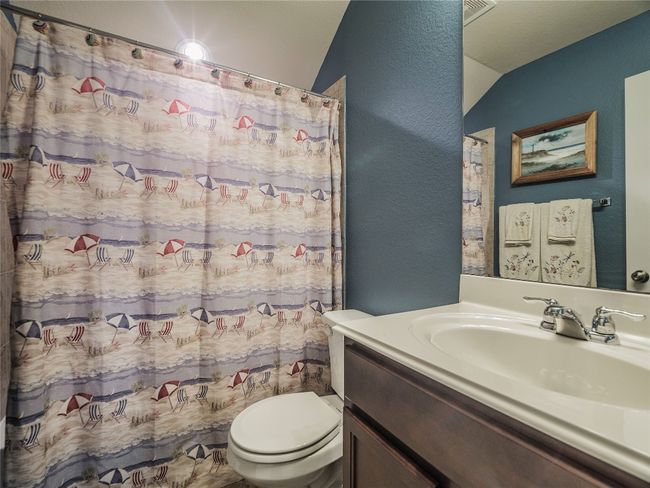Full bathroom featuring toilet, a textured wall, vanity, vaulted ceiling, and a shower with curtain | Image 33