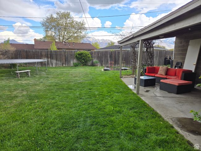 View of yard with outdoor lounge area, a trampoline, a patio, and a fenced backyard | Image 6