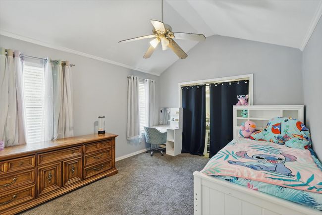 Bedroom with lofted ceiling, carpet floors, ceiling fan, an office area, and ornamental molding | Image 29